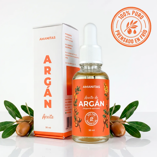 Presentación premium del Aceite de Argán 100% puro de la marca Amanitas. Frasco de vidrio de 30 ml con gotero y su caja minimalista, acompañados de semillas y hojas botánicas de argán (Argania spinosa). Producto extraído por prensado en frío.